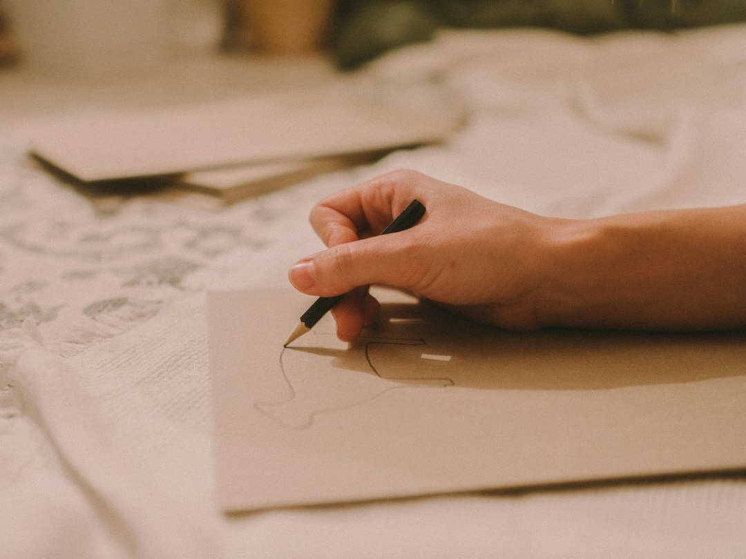 Close-up of hands writing with a fountain pen on paper at a wooden desk